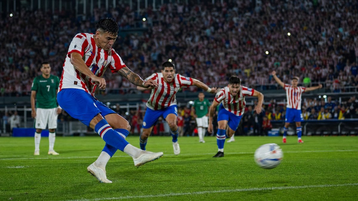 Jogador paraguaio finaliza de longe em estádio lotado durante jogo da Copa.